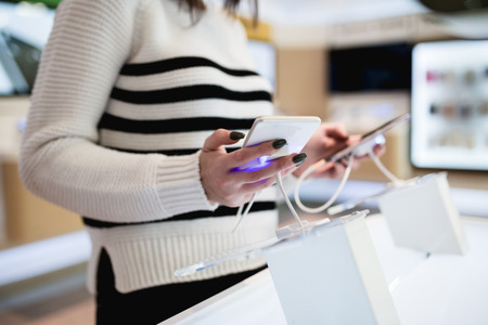 Close up shot of beautiful woman shopping. She standing in mobile phone shop and choosing next model for her.の写真素材