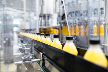 Bottling factory - Orange juice bottling line for processing and bottling juice into bottles. Selective focus.の写真素材