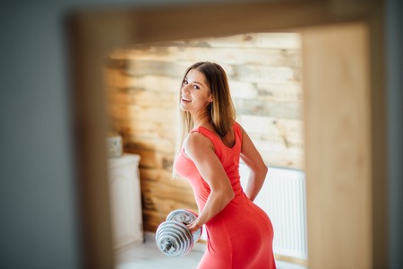 A woman with a dumbbell in a pink dress smilesの写真素材