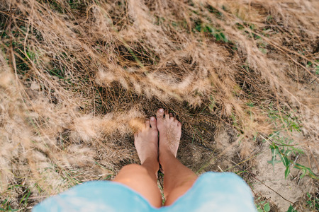 Woman walking barefoot on the grass in blue dressの写真素材