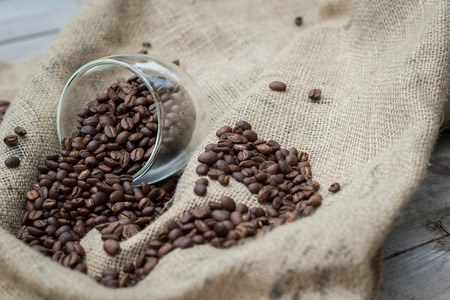 Coffee beans spilling out of glassの写真素材