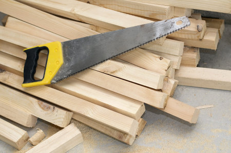 Handsaw with yellow plastic handle on boards