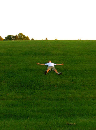 teen in snow angel position on grass hillの写真素材