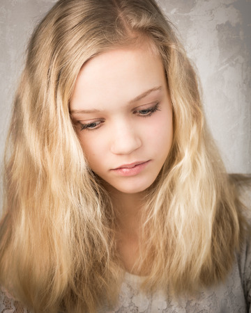 Studio portrait of a beautiful blond teenage girl with long hair and blue eyes isolated against a white background.の写真素材