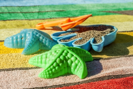 Four Colorful Plastic Beach Toys On A Striped Towelの写真素材