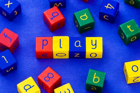 The word  play , written with colored, wooden toy blocks  Arranged on a blue, soft carpet の写真素材