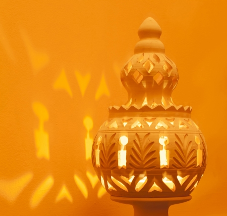 Close-up Of A Decorative North African Terracotta Lamp, Casting Light On An Orange Wall の写真素材