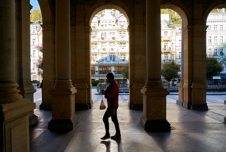 KARLOVY VARY, CZECH REPUBLIC - SEPTEMBER 30, 2018: A tourist walking through the popular Mill...