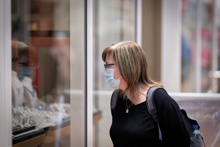Woman goes window shopping with a protective mask because of the existing mask requirement