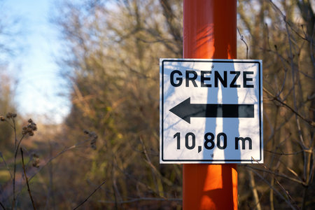 Sign with direction arrow and inscription border 10.80 meters at a forest road in Germanyの写真素材
