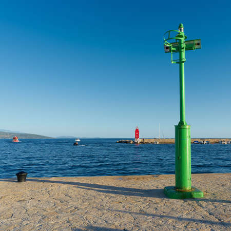 green Lighthouse at a pier in the port of Krk on the Adriatic Sea in Croatiaの写真素材