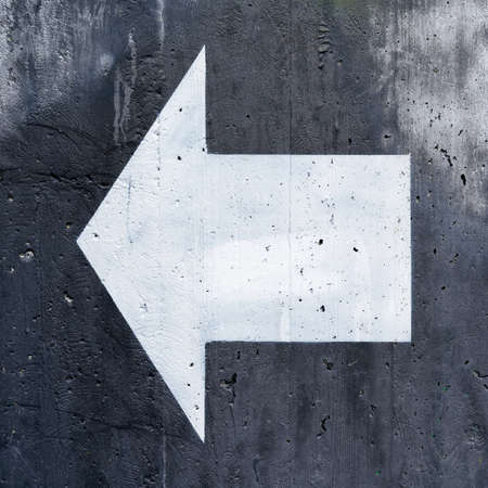 white directional arrow on a black background for orientation on a concrete wallの写真素材