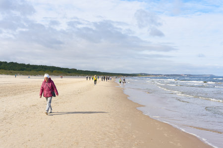Swinoujscie, Poland â October 04, 2022: Strollers on the beach of the Polish Baltic Sea near ÅwinoujÅcie at the end of the season in Octoberのeditorial素材