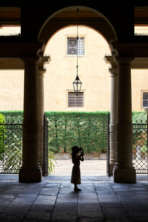 Verona, Italy â August 01, 2023: young girl in a romantic courtyard in the old town of Verona in Italy takes a photo with a smartphoneのeditorial素材