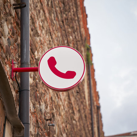 Reference to a public telephone by a sign in the old town of Verona in Italy