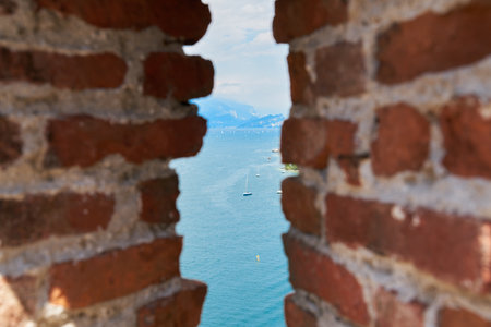 View of Lake Garda from the old town in Malcesine through a gap in a wallの写真素材