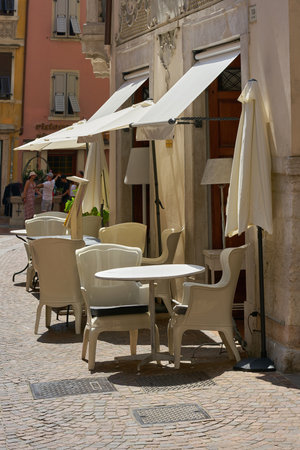 Riva del Garda, Italy â August 13, 2025: Tables and chairs in front of a restaurant in the old town of Riva del Garda on Lake Garda in Italyのeditorial素材
