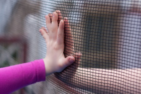 Two children parry their hands through a fenceの写真素材