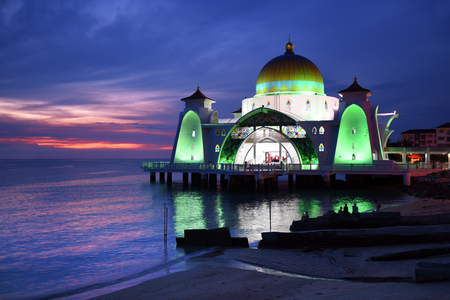 Glowing Strait Mosque of Malacca during sunset and blue hour. The so called swimming Mosque is located at the Historical Malacca City, Malaysia.の写真素材