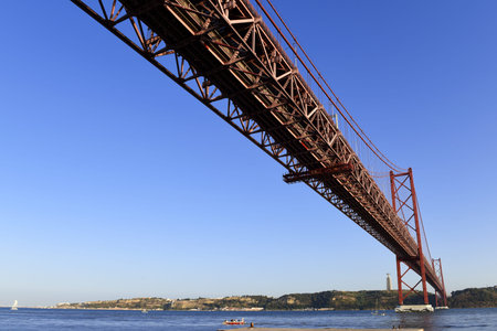 The April 25 Bridge on the left bank of the Tagus River, the monument of Cristo The river overlooks...