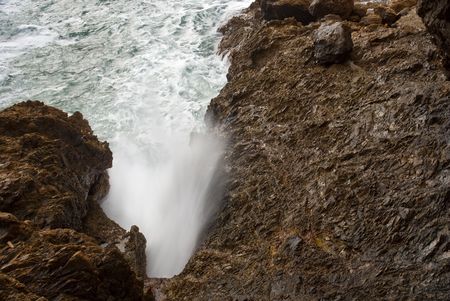 Waves crashing into clefts with water spewing outの写真素材