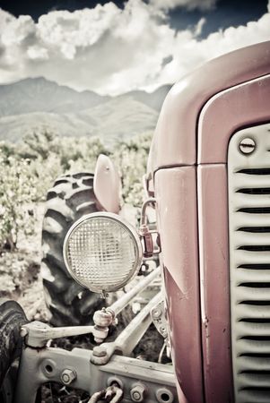 Old red tractor with clouds and vineyards in the backgroundの写真素材