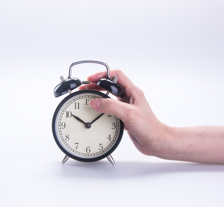 alarm clock with hand. alarm clock with hand on background.の写真素材