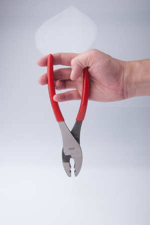 Pliers in hand on the white backgroundの写真素材