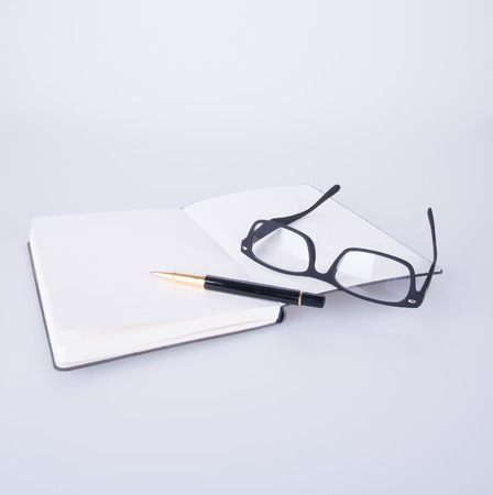 notebook with glasses and pen on the blackgroundの写真素材