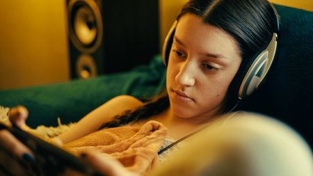 Young woman in headphones listening to music on the couch at home.の写真素材