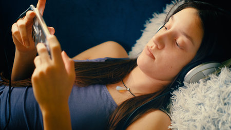 Young woman lying on the sofa and using mobile phone at night.の写真素材