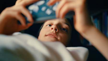 Young woman using mobile phone while lying on the sofa in the living roomの写真素材