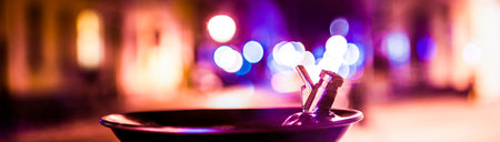 Panoramic view of a macro tap with shallow depth of pyramid lit by colorful light from street at nightの写真素材