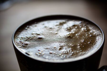 Morning window reflecting in a mug of coffee against the background of a wooden table topの写真素材