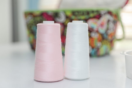Composition with sewing threads, fabric and accessories on wooden background.