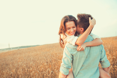 Young couple in love outdoor.d.Couple hugging.Young beautiful couple in love staying and kissing on the field on sunset. Soft sunny colors.の写真素材