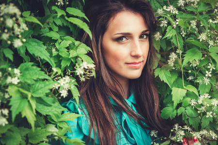 Happy beautiful young woman in spring blossom park. Pretty Girl with Spring Flowers. Fashion Model Outdoorsの写真素材