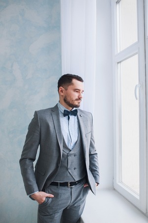 Portrait of a handsome adult man in a gray suit in the studio. The groom is waiting for the brideの写真素材