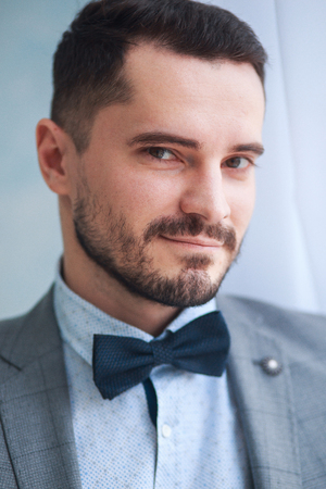 Portrait of a handsome adult man in a gray suit in the studio. The groom is waiting for the brideの写真素材
