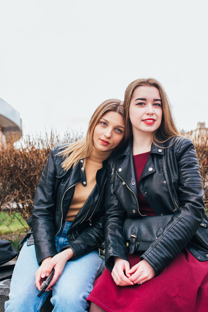 Two young girl friends sitting together and having fun Outdoors. lifestyle.の写真素材