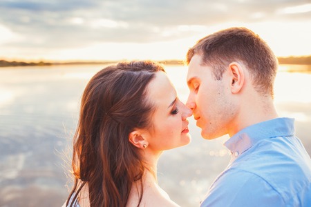 Young beautiful couple in love staying and kissing on the beach on sunset. Soft sunny colors.harmony conceptの写真素材