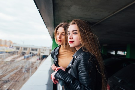 couple of women together in cityscape . Two joyful beautiful fashionable girls on roof . Beautiful city viewの写真素材