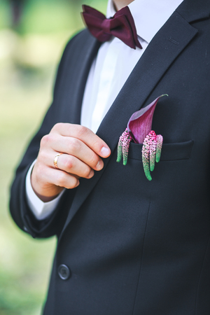 Elegant groom in black costume and purpure bow-tie outdoorの写真素材