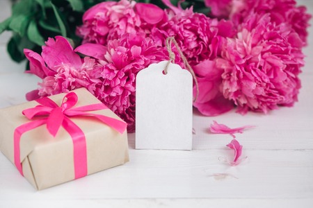 Pink peonies flowers and empty tag on aged wooden background. Top view with copy space. Gift Valentine's Day.の写真素材