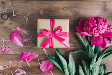 Row of peonies and gift box on wooden background with space for message. Women's or Mother's Day background.の写真素材