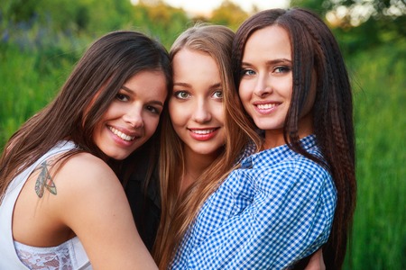 Girlfriends Friendship Happiness Community Concept. Three smiling friends hugging in the natureの写真素材