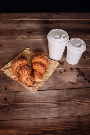 Coffee cup and coffee beans , croissant , on brown wooden tableの写真素材