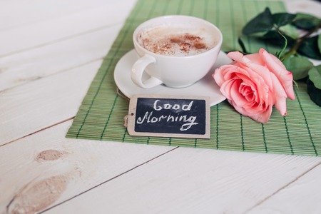 Coffee mug with rose nd notes good morning on white rustic table from above, tasty breakfast, vintage tonedの写真素材