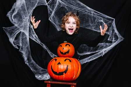 A young boy in halloween costume with pumpkins having funの写真素材