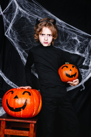 A young boy in halloween costume with pumpkins having funの写真素材